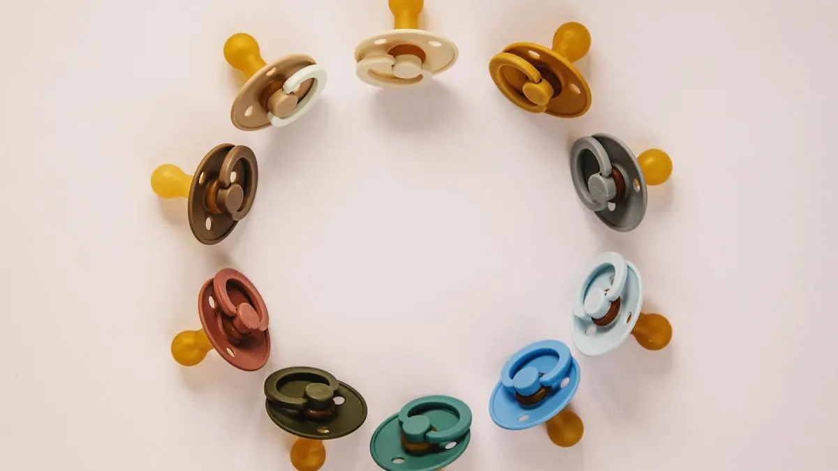Set of multicolored baby pacifiers on table