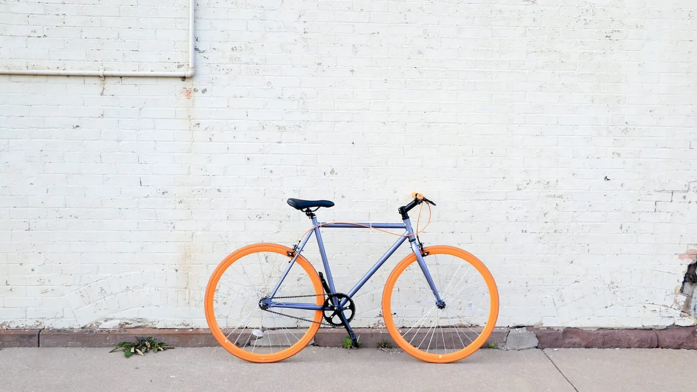 yellow and purple bicycle near white wall at daytime
