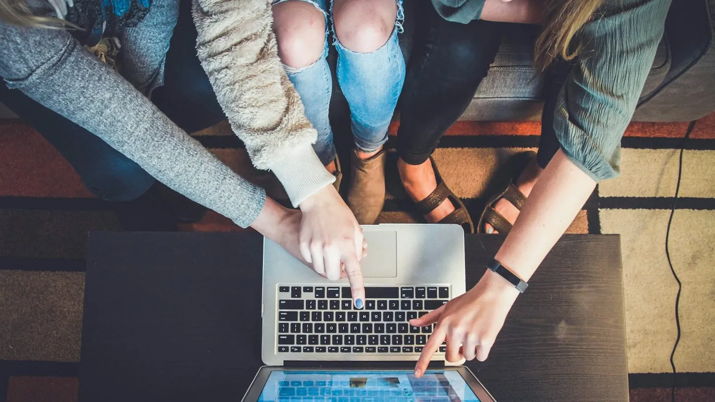 three person pointing the silver laptop computer