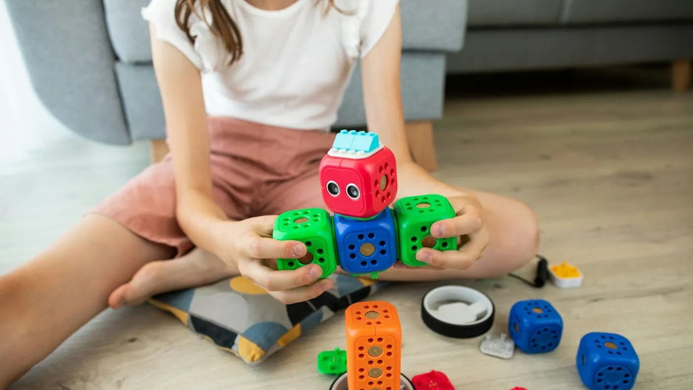 girl in white shirt playing with blue and red car toy