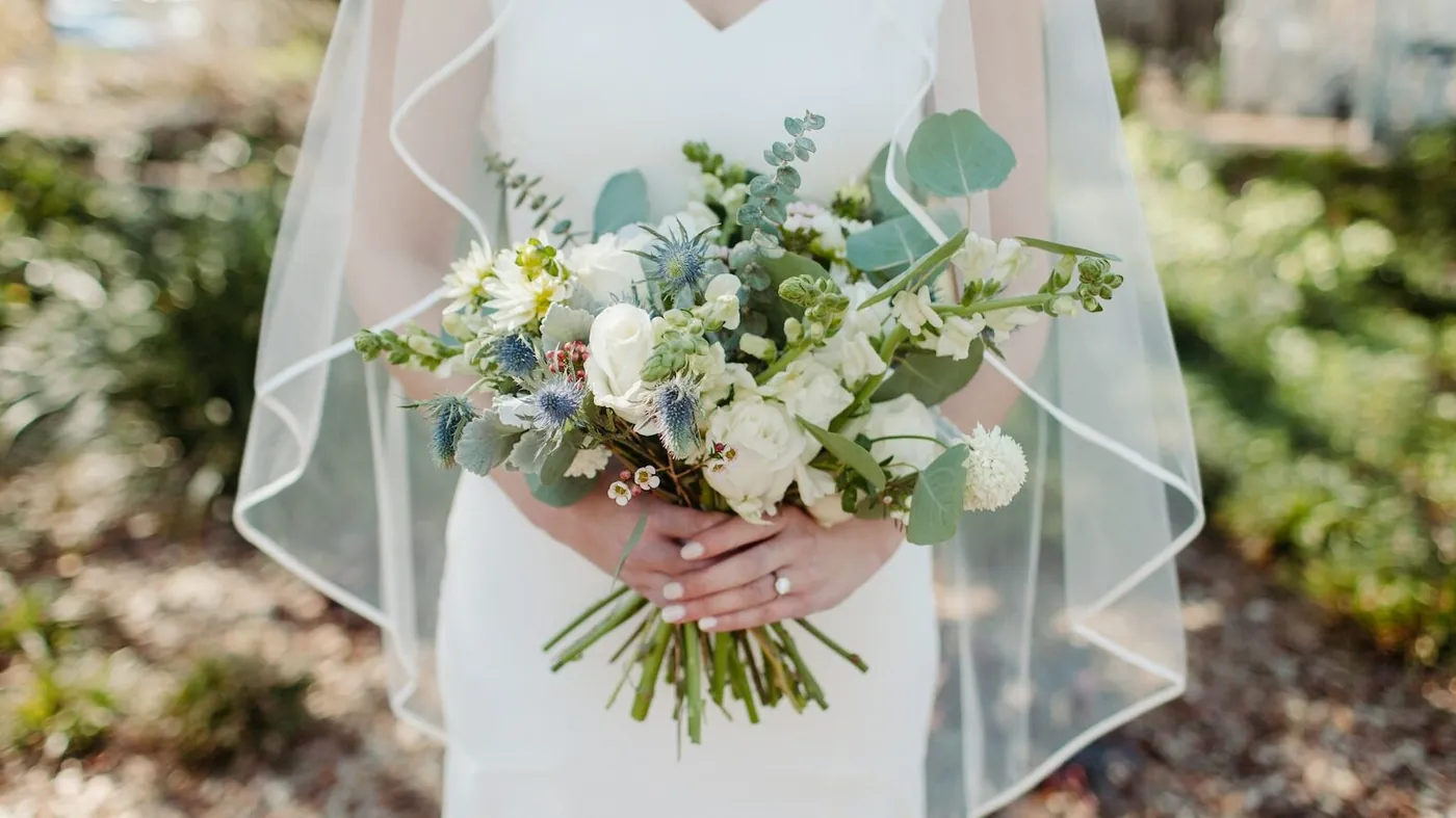 woman in white wedding dress holding white flower bouquet