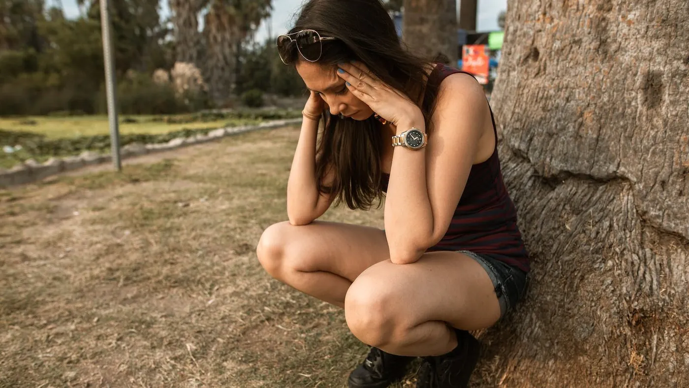 Photo of a Woman Crouching while Her Hands are on Her Head