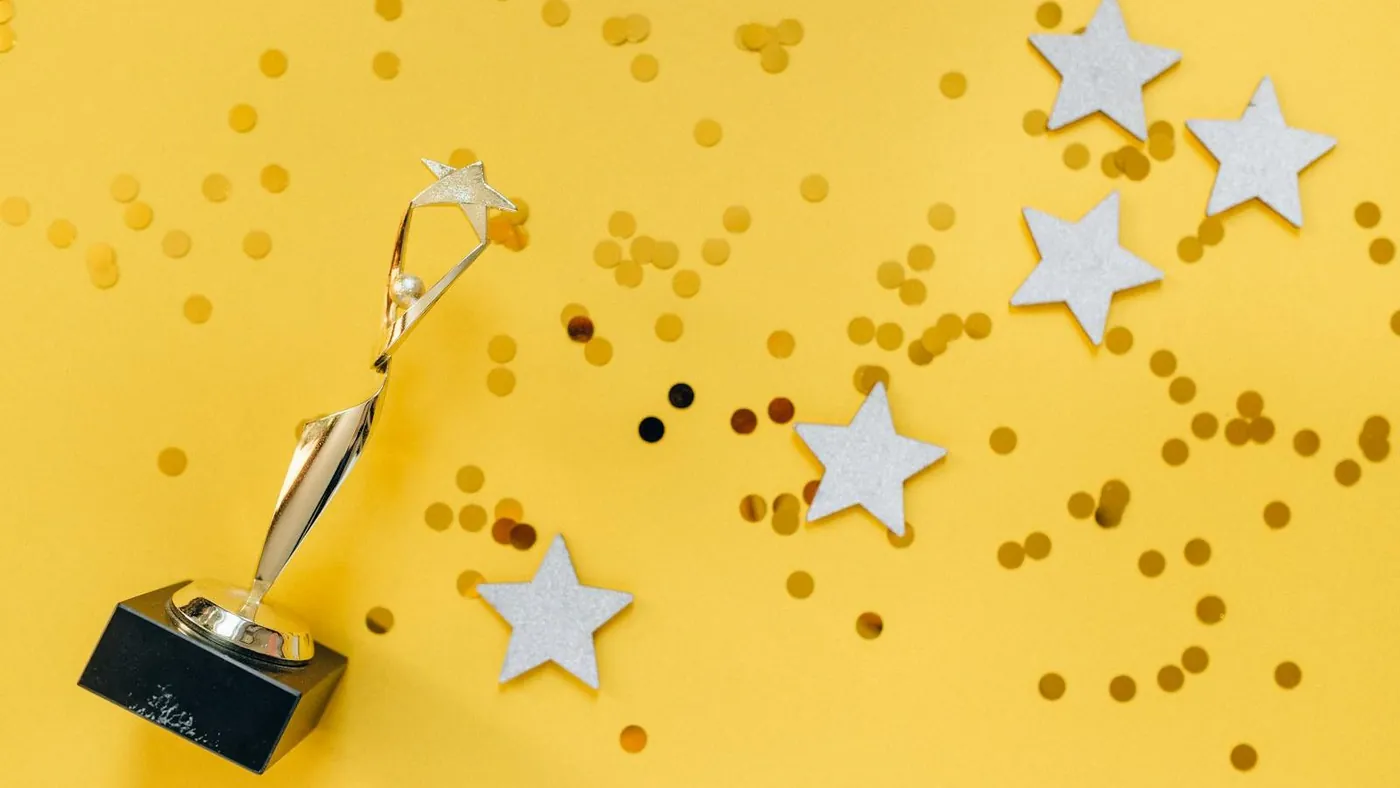 Golden Statuette and Stars on Yellow Background