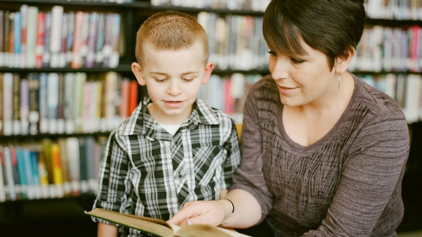 boy in gray sweater beside boy in gray and white plaid dress shirt