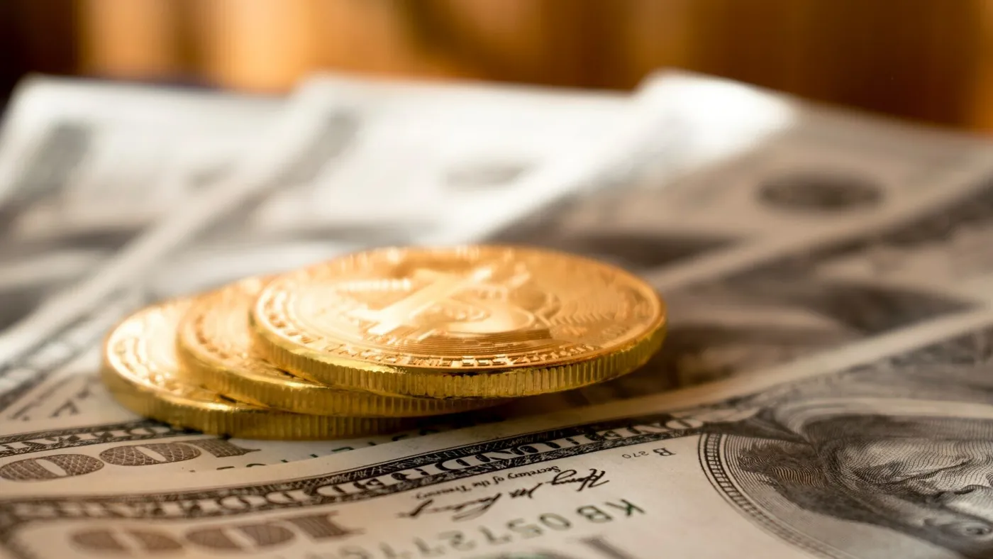 three round gold-colored coins on 100 US dollar banknotes