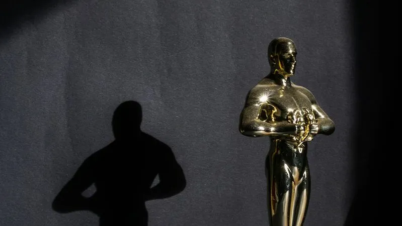 a golden statue of a man standing next to a black wall