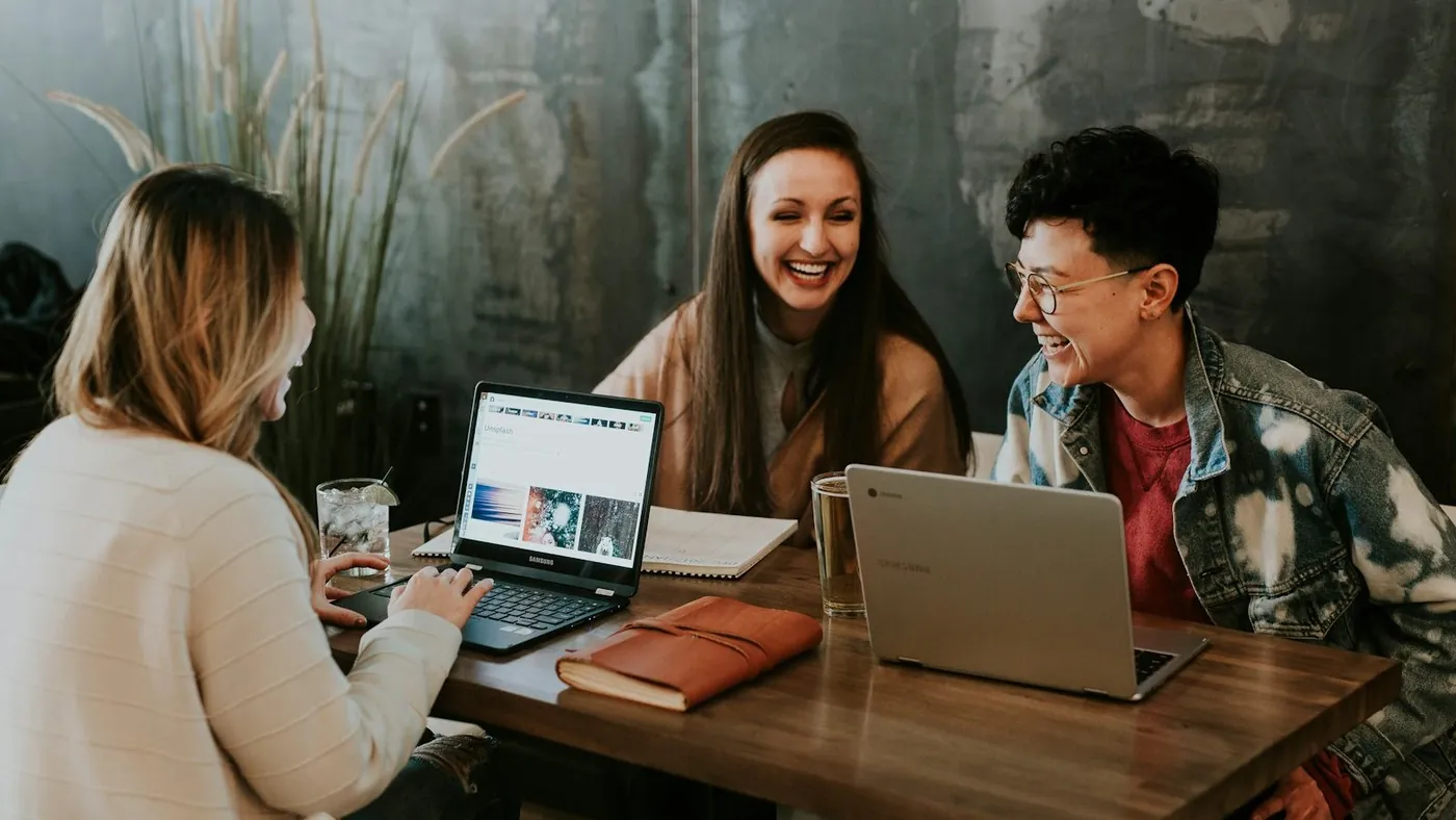 three people sitting in front of table laughing together