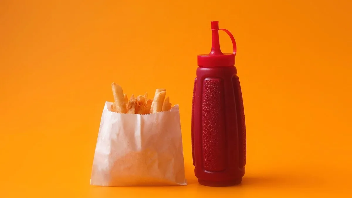 fried fries in white pack beside red squeeze bottle