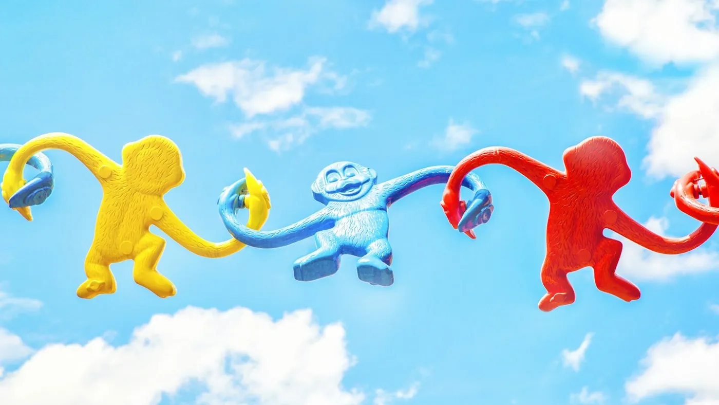 three assorted-color monkey plastic toys holding each other during daytime