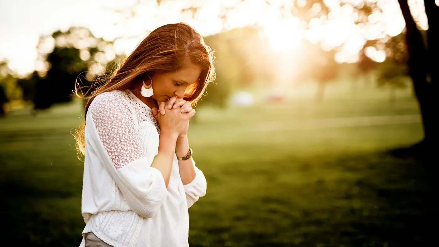 woman praying beside tree