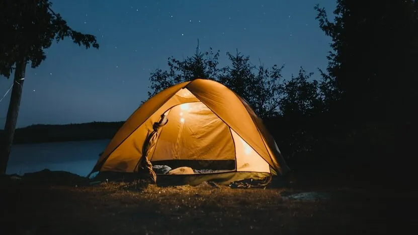 brown dome tent near trees at night