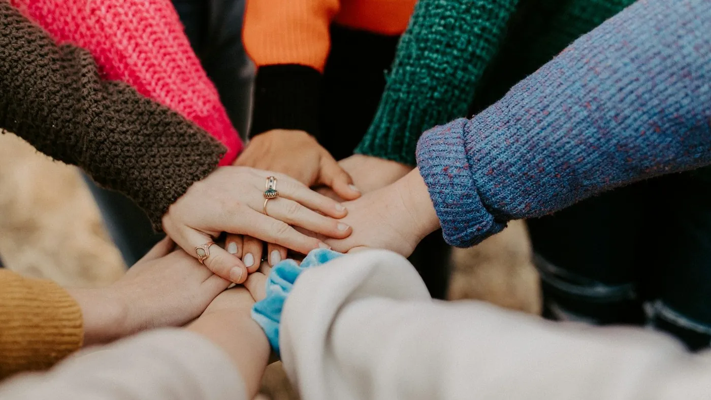 person in red sweater holding babys hand