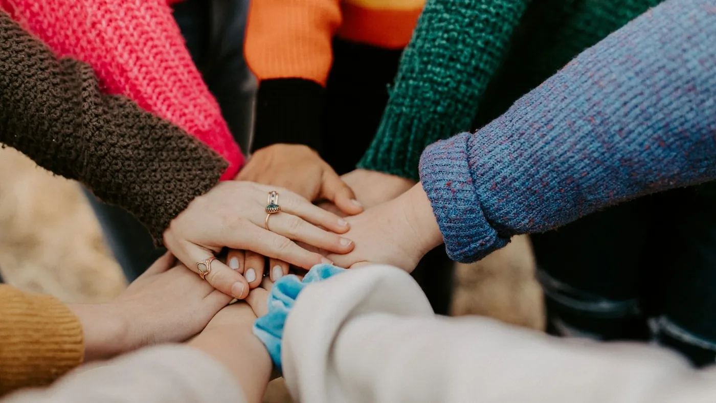 person in red sweater holding babys hand